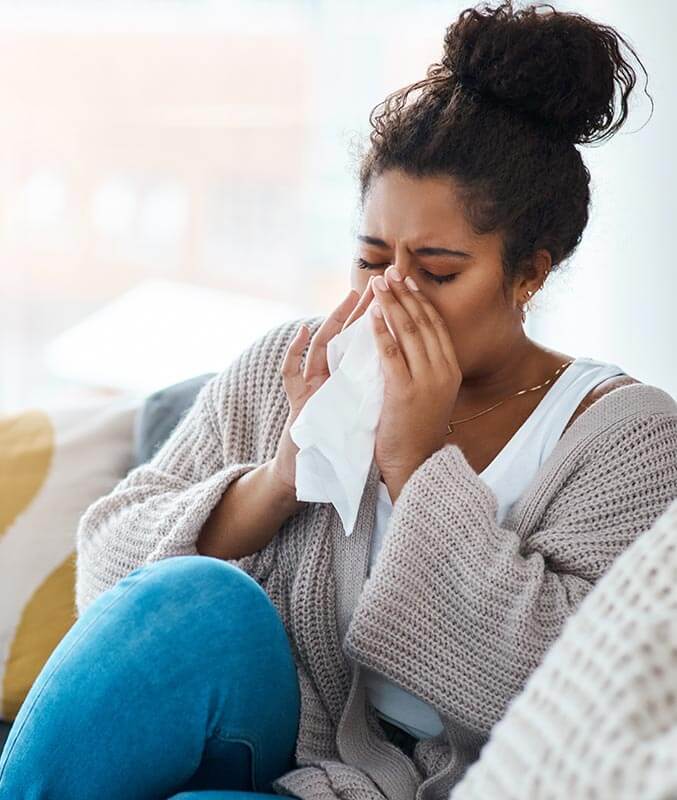 woman sneezing into a tissue