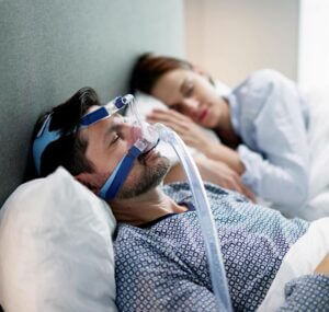 Man sleeping, wearing a CPAP machine Obstructive Sleep Apnea & Snoring