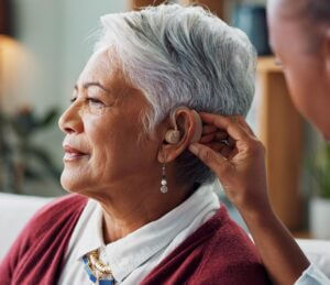 Woman having her hearing aid adjusted