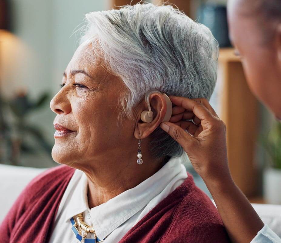 Woman having her hearing aid adjusted
